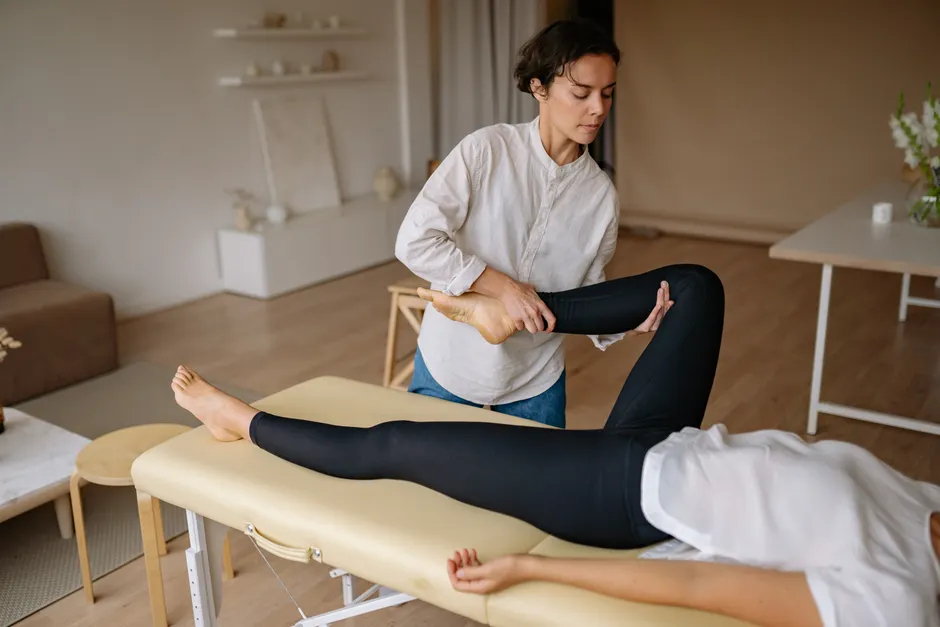 Praticienne travaillant la jambe d'une cliente sur une table de soin