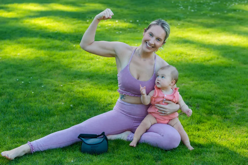 Jeune mère souriante assise dans l'herbe avec son bébé